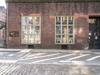 a brick building with a windowed area in front of it next to a parking spot