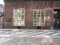 a brick building with a windowed area in front of it next to a parking spot