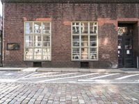 a brick building with a windowed area in front of it next to a parking spot