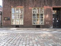 a brick building with a windowed area in front of it next to a parking spot