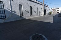 a sidewalk with some shadows on it near a brick building and electrical wires in the sky