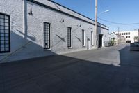 a sidewalk with some shadows on it near a brick building and electrical wires in the sky