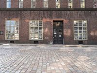 a brick building with many windows and a black door in the center of the image