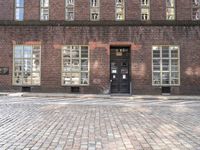 a brick building with many windows and a black door in the center of the image