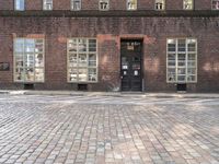 a brick building with many windows and a black door in the center of the image