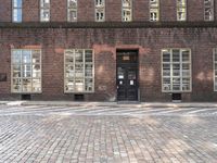 a brick building with many windows and a black door in the center of the image