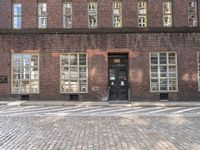 a brick building with many windows and a black door in the center of the image