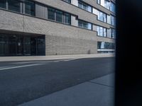 the street has a brick building and lots of windows in it, and a bus is moving by