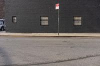 a large brick building with window, and no parking sign on the corner of the street