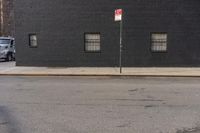 a large brick building with window, and no parking sign on the corner of the street