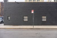 a large brick building with window, and no parking sign on the corner of the street