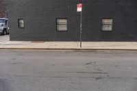 a large brick building with window, and no parking sign on the corner of the street