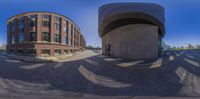 a group of buildings sitting in the middle of a brick city street intersection with a circular reflection in the middle