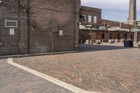 brick courtyard with red stone flooring in front of a factory building and silos