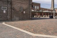 brick courtyard with red stone flooring in front of a factory building and silos