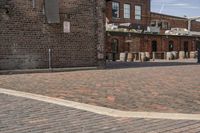 brick courtyard with red stone flooring in front of a factory building and silos