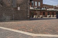 brick courtyard with red stone flooring in front of a factory building and silos