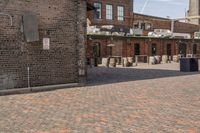 brick courtyard with red stone flooring in front of a factory building and silos