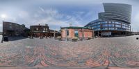 circular picture of a brick courtyard with buildings in the background that include a restaurant and other small outdoor space