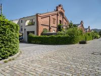 a large brick driveway that goes across the side of a building and a hedge lined parking lot