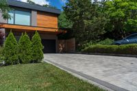 a driveway with brick pathway near two bushes and cars parked outside the house in the evening