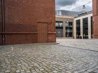 the walkway between two red bricks and a building with the outside entrance to it with a bench