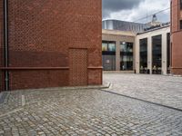 the walkway between two red bricks and a building with the outside entrance to it with a bench