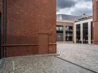 the walkway between two red bricks and a building with the outside entrance to it with a bench