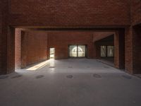 a view of a brick hallway with multiple openings, and sunlight from one doorway, through the floor