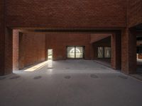 a view of a brick hallway with multiple openings, and sunlight from one doorway, through the floor