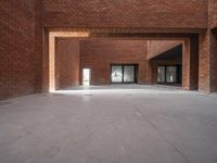 a view of a brick hallway with multiple openings, and sunlight from one doorway, through the floor