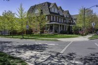 a two story brick house on an upscale street corner with grass and trees surrounding the house