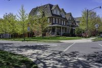 a two story brick house on an upscale street corner with grass and trees surrounding the house