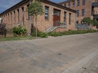 the street is lined with bricks near buildings and trees in front of it for people to walk