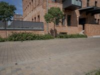 the street is lined with bricks near buildings and trees in front of it for people to walk