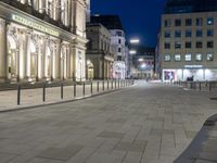 a brick road with a couple people walking on it at night time in europe - city square