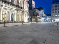 a brick road with a couple people walking on it at night time in europe - city square