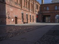 there is a brick road in the middle of town near the tall building that houses the factory and warehouse