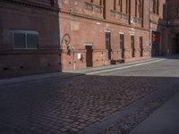 there is a brick road in the middle of town near the tall building that houses the factory and warehouse