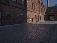 there is a brick road in the middle of town near the tall building that houses the factory and warehouse