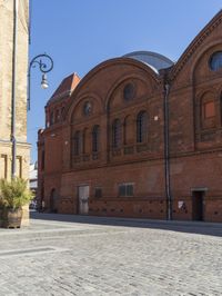 a brick road leading to an old building with tall windows and a clock on each side