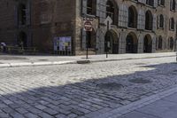 a motor scooter parked at the side of a brick road near an old building