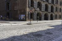 a motor scooter parked at the side of a brick road near an old building