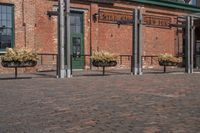 large bricks sitting on a brick sidewalk in front of a building with a bunch of flower pots