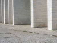 this is a photo of a brick street in front of a building that has columns and other things on the ground in front of it