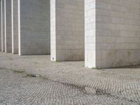 this is a photo of a brick street in front of a building that has columns and other things on the ground in front of it