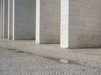 this is a photo of a brick street in front of a building that has columns and other things on the ground in front of it