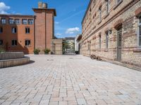 a brick walkway in an old brick building courtyard with a bench and firepith