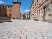 a brick walkway in an old brick building courtyard with a bench and firepith