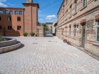 a brick walkway in an old brick building courtyard with a bench and firepith